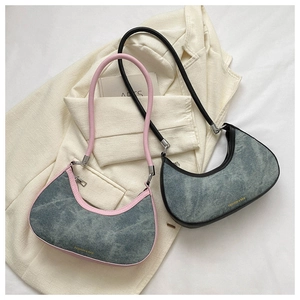 Detailed view of pink and black crescent underarm bags with washed denim texture on a blazer