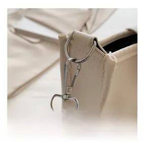 Detail of silver metal spring clasp and striped fabric strap on beige leather bucket bag