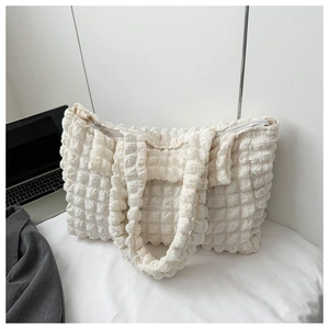 Close-up of beige popcorn bubble texture fabric and zipper on a stylish shoulder bag