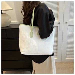 Gros plan d'un sac cabas tissé blanc avec anses vert clair porté par un mannequin