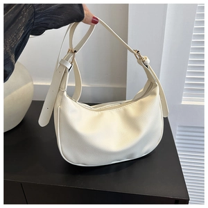 Detail of cream half-moon hobo bag showing fine lychee grain texture and gold metal buckle