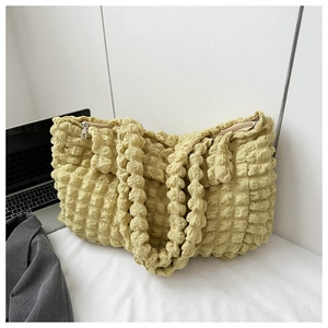 Detailed macro shot of light yellow bubble texture fabric and silver zipper of tote bag