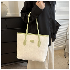 Détail du sac cabas tissé beige pour femme avec anses vertes porté à l'épaule par un mannequin