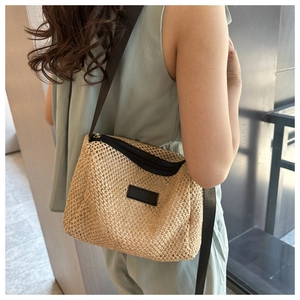 Détail du sac en paille beige tissé main avec fermeture éclair noire et bandoulière