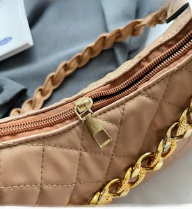 Dettaglio ravvicinato della cerniera dorata e trama trapuntata della borsa beige a tracolla