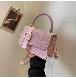 Close-up of pink crossbody bag featuring sparkling rhinestone handle and gold buckle detail