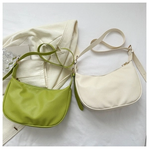 Detailed top view of half-moon leather bags in green and white on white fabric