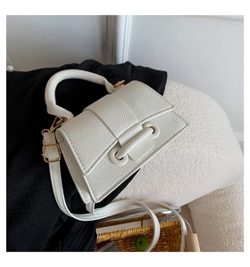 Detailed macro of white litchi textured PU leather bag with gold buckle hardware