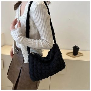 Détail du sac bandoulière noir avec texture plissée et forme de croissant moderne