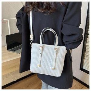 Detailed shot of white striped bucket bag featuring golden hardware and woven texture finish