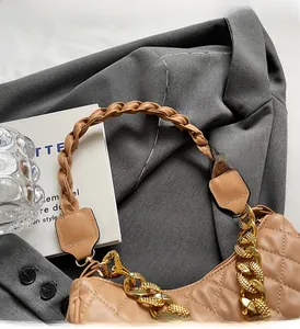 Dettaglio borsa in pelle trapuntata con manico intrecciato e catena in metallo oro