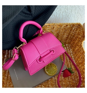Close-up of fuchsia lychee-grain leather mini bag inside a woven basket setting