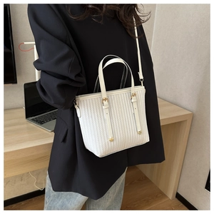 Close-up of white vertical striped bucket bag with gold hardware and shoulder strap