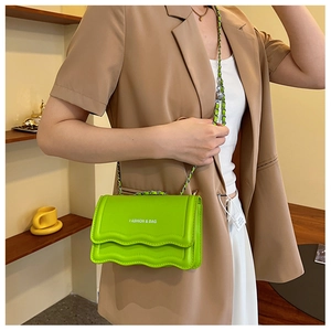 Detail of neon green wave edge crossbody bag with metal chain strap and white logo print