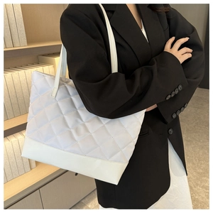 White quilted tote bag shown in a professional setting worn on a model's shoulder