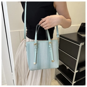 Detailed shot of mint green bucket bag with vertical stripe texture and golden hardware