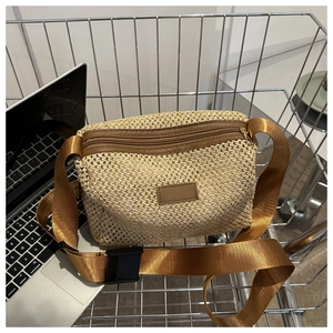 Détail du sac bandoulière en paille tressée avec bordure en cuir brun et sangle