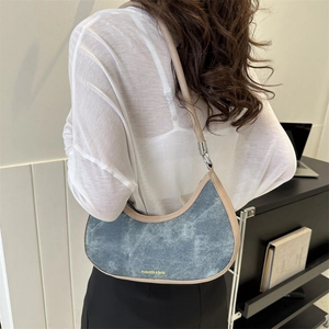 Light blue denim crescent shoulder bag with beige leather trim and gold text detail
