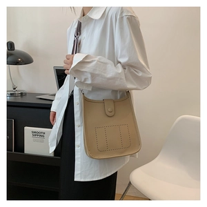 Chic beige lychee leather bucket bag showing U-shaped silhouette and perforated design