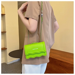 Detail of neon green wave pattern shoulder bag with metal chain strap and logo