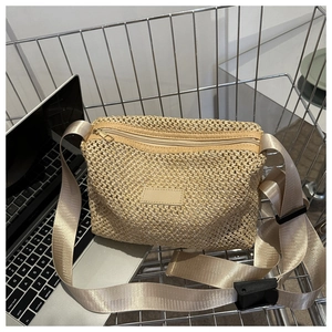Détail du sac en paille tissée montrant la texture, la bandoulière et le zip