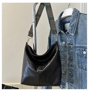 Close-up of large black leather tote bag with colorful ethnic geometric wide strap