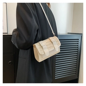 Détail de la texture tissée du sac beige à bandoulière avec fermeture à boucles élégante