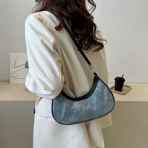 Blue denim crescent underarm bag with black leather trim and thin shoulder strap
