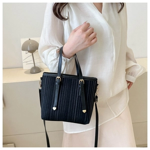 Detailed view of black vertical stripe tote bag with gold hardware and long strap