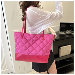Detail of rose red quilted tote bag showing waterproof fabric and leather bottom