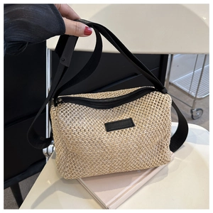 Détail d'un sac bandoulière en paille tressée avec texture nid d'abeille et sangle noire