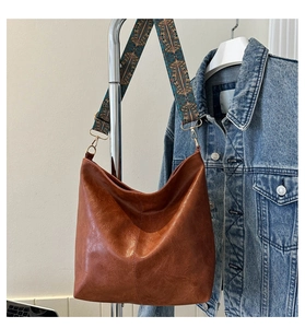 Detail of caramel brown PU leather tote bag with ethnic style wide woven shoulder strap