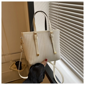 Detailed view of cream striped bucket bag with gold hardware and detachable strap