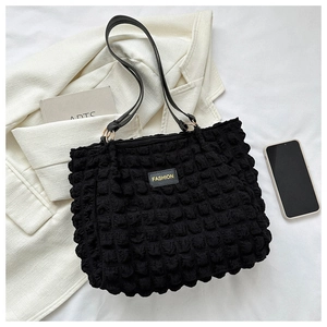 Detail of black pleated bubble texture tote bag with leather strap and fashion label