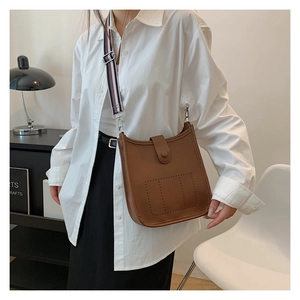 Detail of brown litchi pattern leather bucket bag with perforated design and wide strap