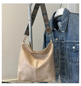 Detail of beige hobo bag with vintage ethnic pattern wide strap on denim jacket