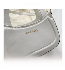 Close-up of white leather handbag featuring a gold embossed logo and precision stitching