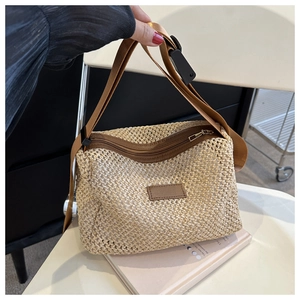 Détail du sac tressé montrant la texture paille naturelle et l'écusson en cuir marron