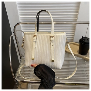 Detailed shot of white vertical striped tote bag featuring woven texture and gold hardware