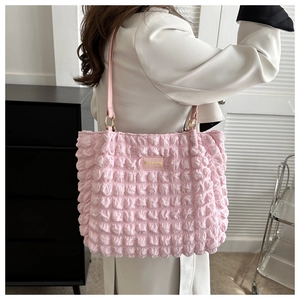 Pink bubble quilted tote bag with golden metal logo shown on model wearing a white coat