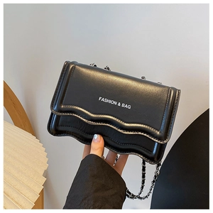 Detail of the wave-pattern flap and silver chain strap on the black leather bag