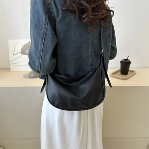 Minimalist black hobo shoulder bag in textured leather worn by a model in a modern style