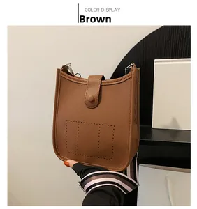 Detail view of brown lychee grain leather bucket bag with perforated H logo and striped strap