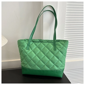 Close-up of vibrant green quilted nylon tote bag with durable faux leather base panel