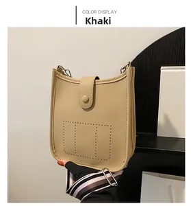 Detail of khaki litchi grain bucket bag with perforated design and woven shoulder strap