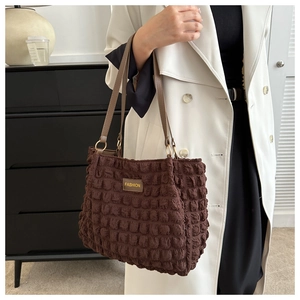Detail of brown bubble textured tote bag with Fashion patch and smooth leather handle