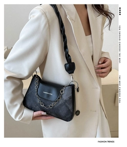 Détail du sac à bandoulière en cuir noir avec chaîne fleurie et bandoulière tressée