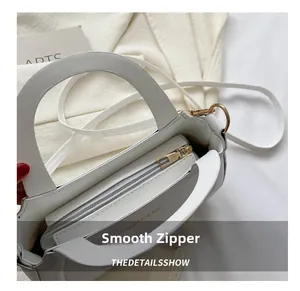 Detailed view of the smooth golden zipper and premium white leather texture on a shoulder bag