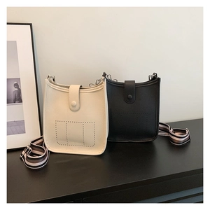 Close-up of pebble-grain mini bucket bags with H-perforated detail and striped straps