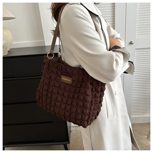Detail of dark brown tote bag with bubble texture and golden metal hardware ring
